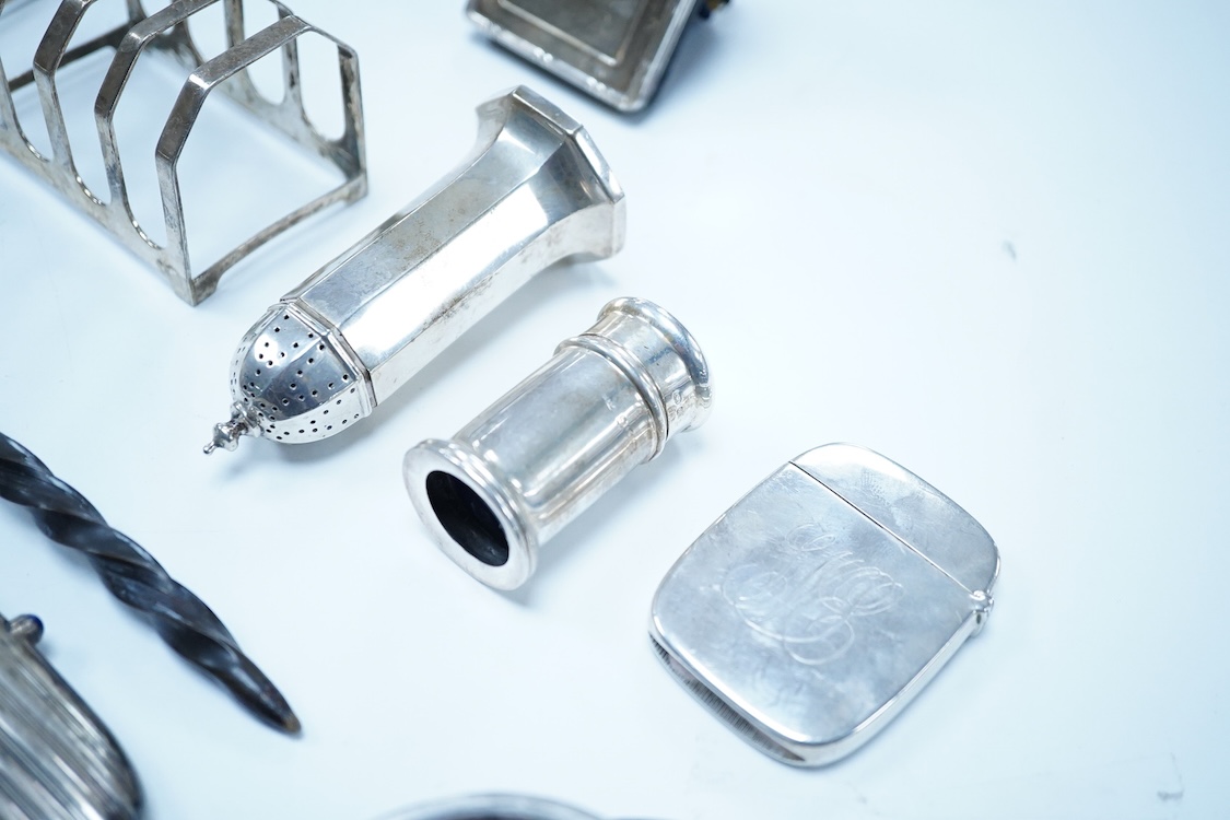A group of assorted silver, to include a pair of modern five bar toast racks, a George V card case, a sterling vesta case, four assorted condiments, two mounted toilet bottles, mounted timepiece, a modern wooden handled